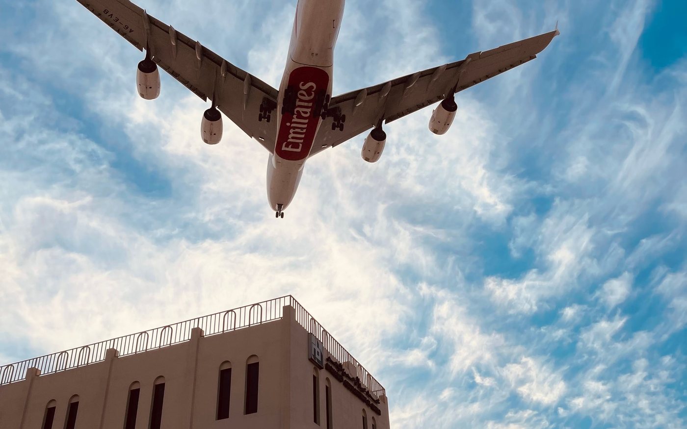 An Emirates jet passing low over buildings in Dubai