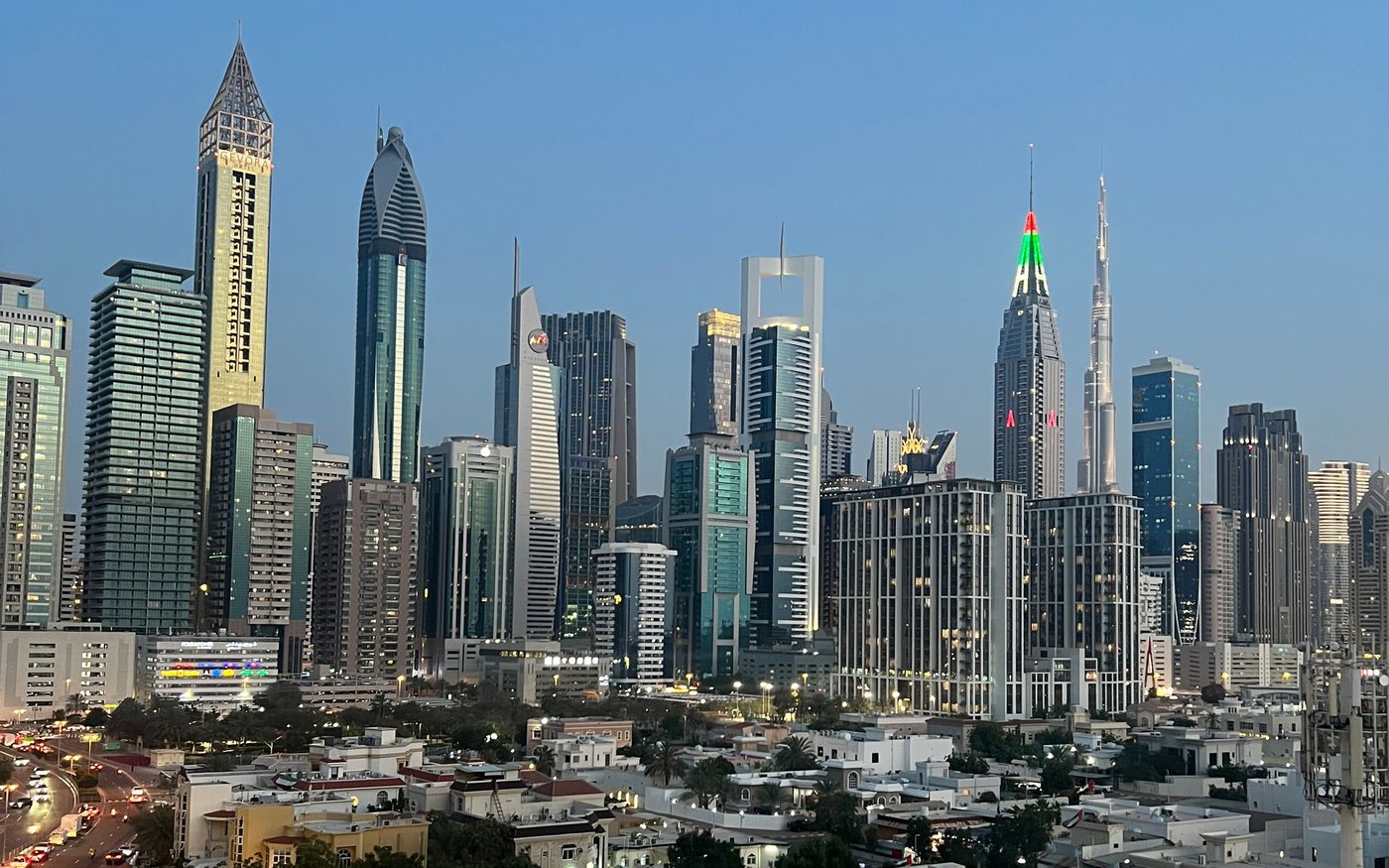 Sheikh Zayed Road towers rising behind low-rise villas at dusk
